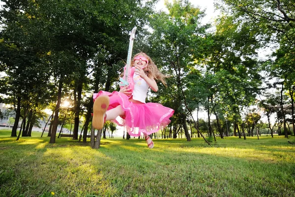 Meisje van de baby springen met een speelgoed-gitaar — Stockfoto