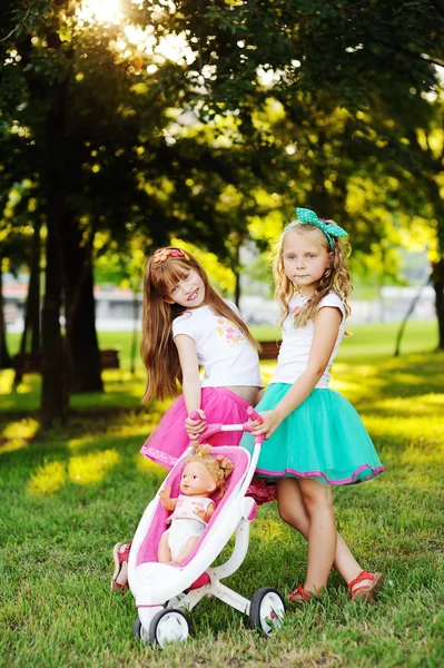 Zwei kleine Mädchen mit einem Kinderwagen — Stockfoto