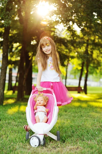 Mädchen trägt Puppe im Kinderwagen — Stockfoto