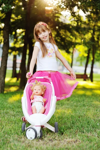 Mädchen trägt Puppe im Kinderwagen — Stockfoto