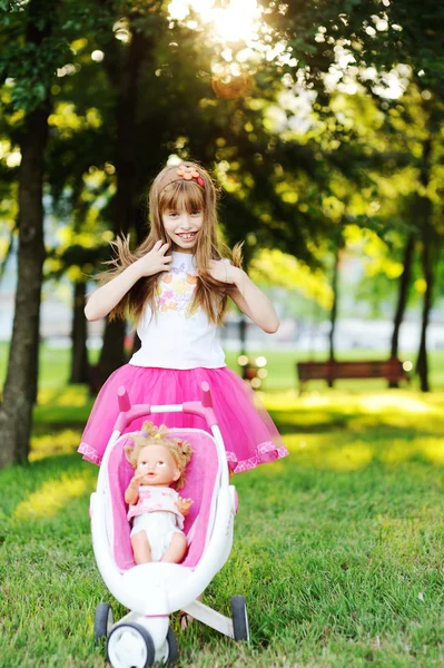 Девочка носит куклу в коляске — стоковое фото
