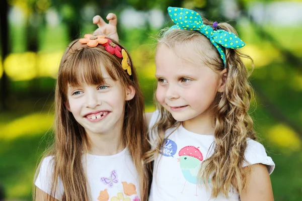 Two little girls grimace on the background of the park — Stock Photo, Image