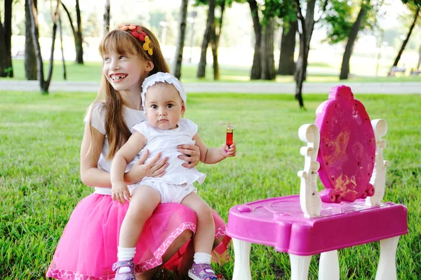 Younger and older sister in the mirror lipstick — Stock Photo, Image