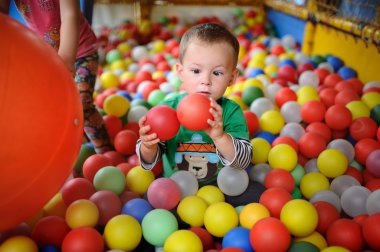 baby boy looking with surprise at the colored balls. child squin clipart