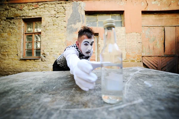 Mime reaches for a bottle of alcohol. Alcoholism — Stock Photo, Image