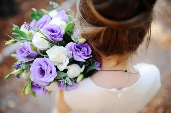 Menina segurando um buquê de casamento de flores brancas e roxas — Fotografia de Stock