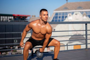 Genç adam dışarıda kettlebell ile egzersiz yapıyor. Fitness, spor ve sağlıklı yaşam tarzı konsepti.