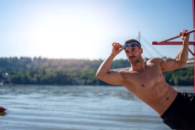 Sahilde formda bir vücut geliştirici. Kumsaldaki çekici genç adam cankurtaranı..
