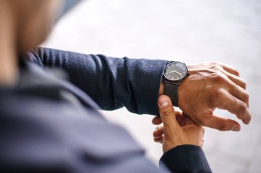 İş adamı saatine bakıyor, saati izliyor.