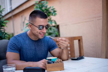 Yakışıklı ve başarılı bir adamın portresi kafede oturup kahve içiyor. Adamın biri güzel bir terasta oturmuş bitkilerle kahvaltı yapıyor..