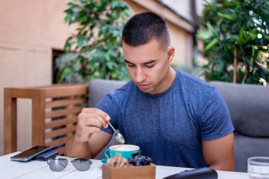Yakışıklı ve başarılı bir adamın portresi kafede oturup kahve içiyor. Adamın biri güzel bir terasta oturmuş bitkilerle kahvaltı yapıyor..