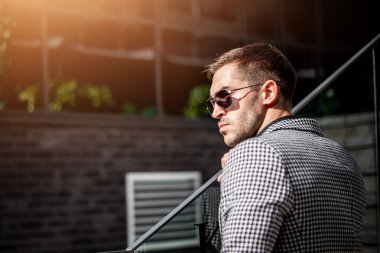 Şehirde işlerle uğraşan genç bir adamın portresi. Başarılı bir iş adamı ofisinin yakınında fotoğrafçıya poz veriyor.