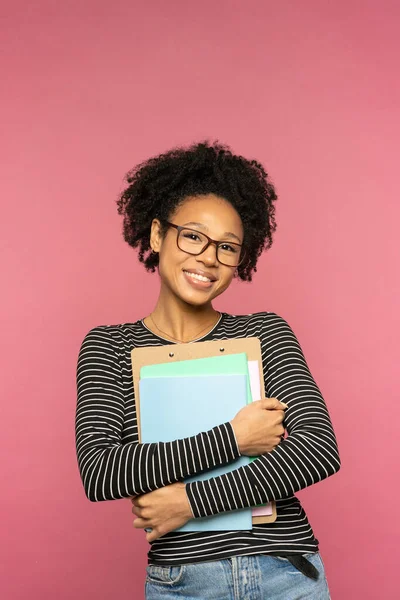 若い幸せなアフリカ系アメリカ人の家庭教師や教師の女性ピンクのスタジオの壁に隔離された 女子高生はノートと笑顔で眼鏡をかける 大学と高校 大学広告の概念 — ストック写真
