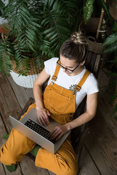 Giovane Giardiniere Femminile Seduta Sedia Legno Serra Utilizzando Computer Portatile — Foto Stock