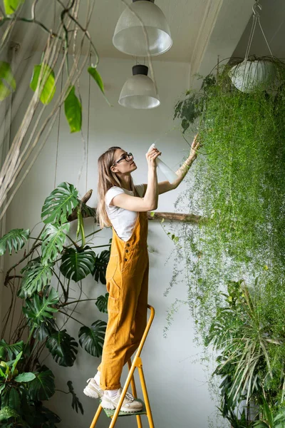 Turuncu Tulumlu Genç Kadın Bahçıvan Çiçek Dükkanında Merdiven Üzerinde Duran — Stok fotoğraf