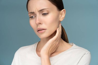 Closeup of sick sad woman checking lymph nodes, caught cold, suffering from throat problems, isolated on studio blue background clipart