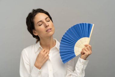 Tired overheated woman employee unbuttons top button of blouse, using wave fan suffer from heat sweating clipart