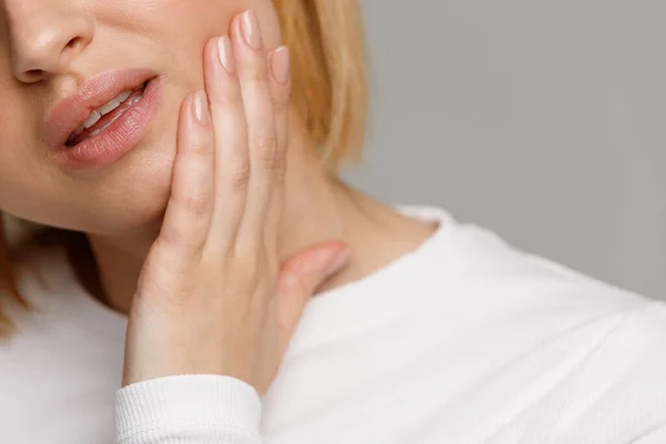 歯の問題や歯の病気 若い女性の痛みを感じ 手で頬を保持し 悪い歯痛 灰色の背景に隔離された 自由な空間に苦しんで閉じます 繊細なエナメルコンセプト — ストック写真