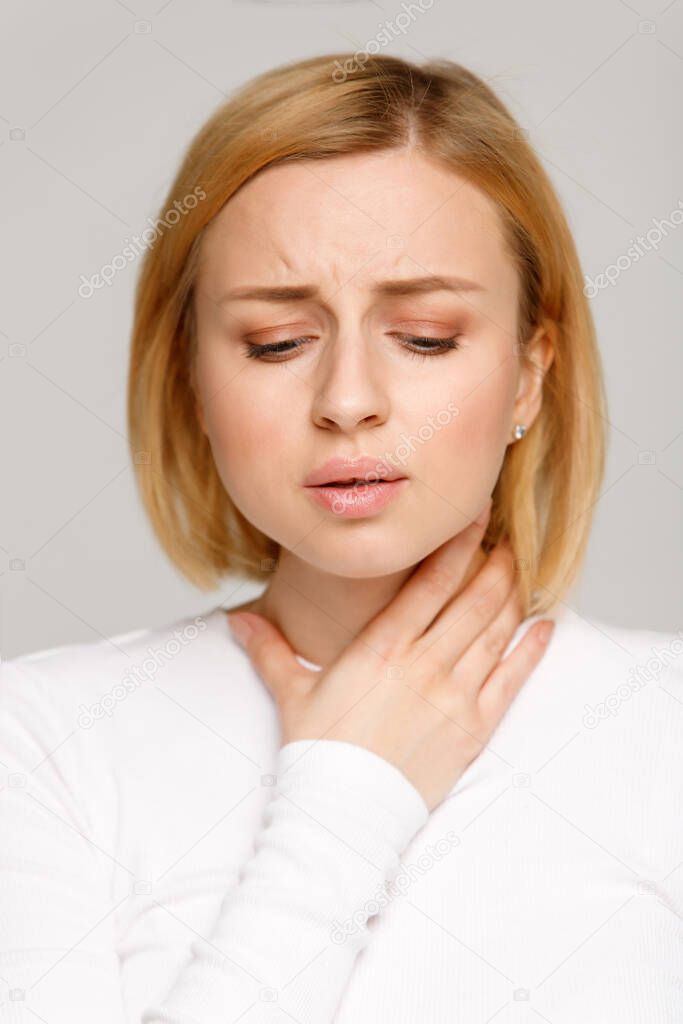 Closeup studio portrait of sick young woman suffering from throat problems. Thyroid gland, painful swallowing, tonsillitis concept. Inflammation of the upper respiratory tract