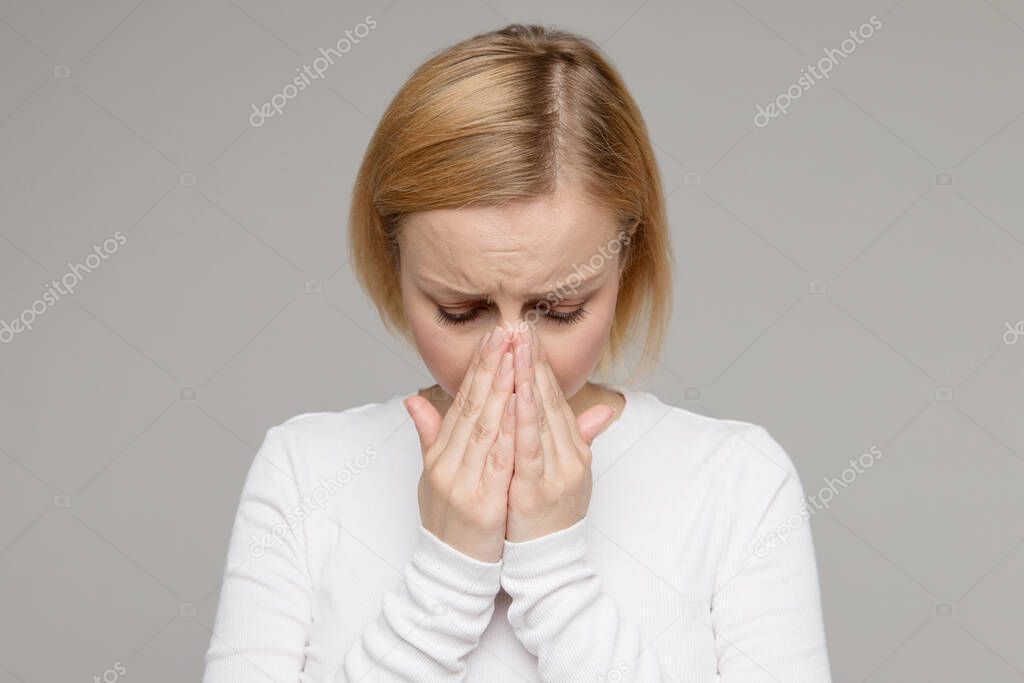 Studio portrait of sad tired woman covering her face with palms, isolated on grey background. Crying female in depression. Love relationship. Stress, bad news, sadness.