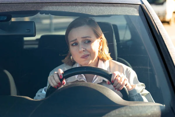 Woman drives her car for the first time, tries to avoid a car accident, is very nervous and scared, worries, clings tightly to the wheel. Inexperienced driver in stress and confusion after an accident
