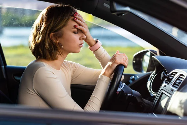 疲れ女性のドライバは 頭痛の種を感じ 彼女の車の中に座って 頭に手を維持し 不安を感じる 交通渋滞で車を運転した後停止します — ストック写真