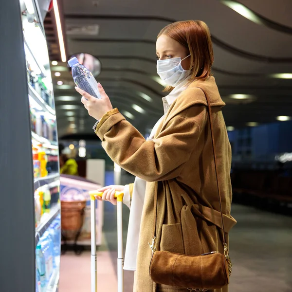 在机场 白种人女性顾客戴着面部保护膜 购买和选择水瓶 阅读标签上的信息 Coronavirus Covid 19流行病在美国流行期间购买食物 — 图库照片