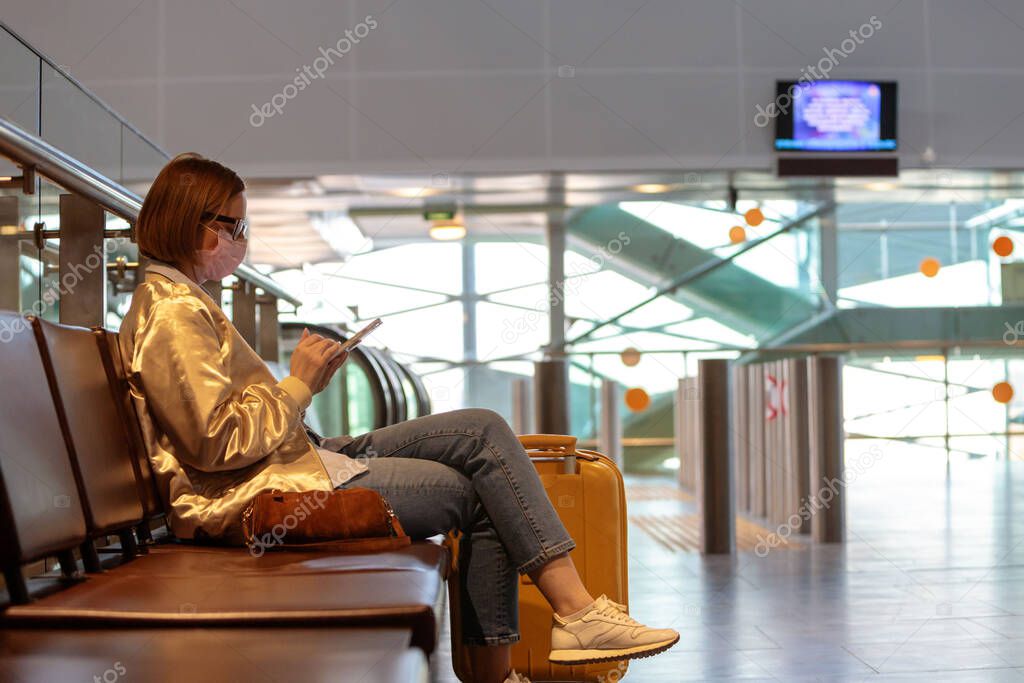 Woman upset over flight cancellation, writes message to family, sitting in almost empty airport terminal due to coronavirus pandemic/Covid-19 outbreak travel restrictions, collapse. Quarantine measure