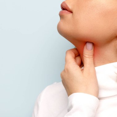 Close up of woman touches fingers of sore throat, isolated on blue background. Thyroid gland, painful swallowing, tonsillitis, laryngeal swelling concept. Inflammation of the upper respiratory tract clipart