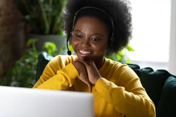 Souriant Afro femme porter casque parler appel vidéo, à l'aide d'un ordinateur portable, regarder le travail webinaire de la maison — Photo