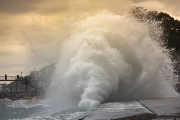 Huge stormy waves crashing near the city embankment. Big sea wave splash. Giant waves on a stormy day in Yalta. Power of nature, storm