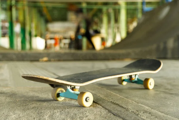 Closeup of skateboard in skateboard park, indoors, blurred background. Youth extreme sports, urban subculture concept.