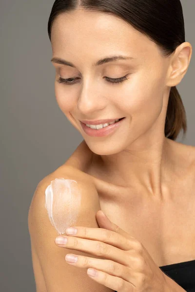 Donna che applica crema solare o lozione idratante cosmetica sulla pelle idratata perfetta sulla spalla — Foto Stock