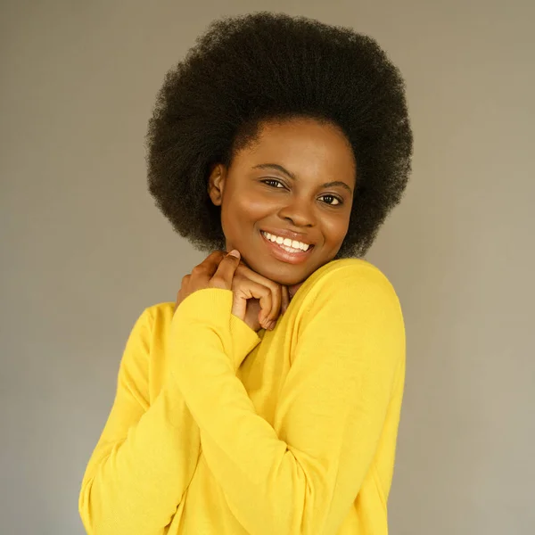 Happy Afro American millennial woman with afro hair style wear yellow sweater posing over grey wall — Stock Photo, Image