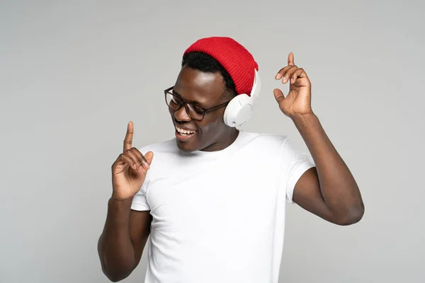 Glücklicher Afro-Mann trägt drahtlose Kopfhörer und genießt es, Musik zu hören, mit erhobenen Händen zu tanzen — Stockfoto