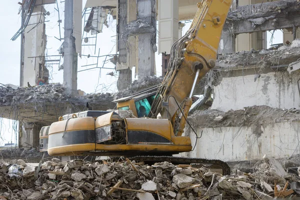 Closeup of special hydraulic excavator-destroyer during operation, ruins of a building on background. Ultra high demolition equipment