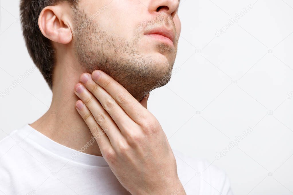Close up of sick man suffering from throat problems, grey background, isolated. Lymph glands, painful swallowing, pharyngitis, laryngeal swelling concept. Inflammation of the upper respiratory tract