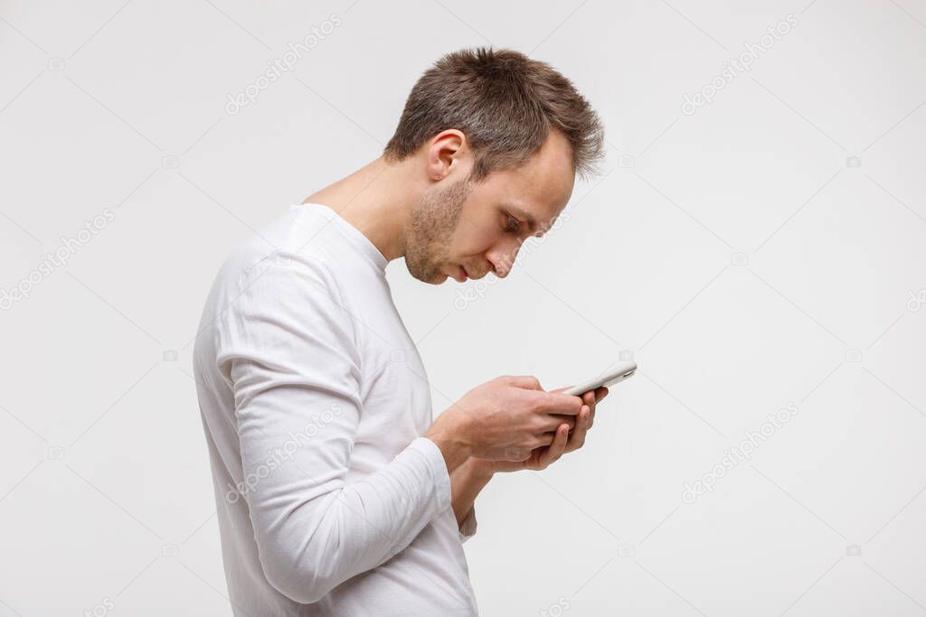 Close up portrait of man looking and using smart phone with scoliosis, side view, isolated on gray background. Rachiocampsis, kyphosis curvature of neck, Incorrect posture