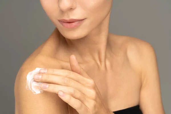 Donna che applica crema solare o lozione idratante cosmetica sulla pelle idratata perfetta sulla spalla — Foto Stock