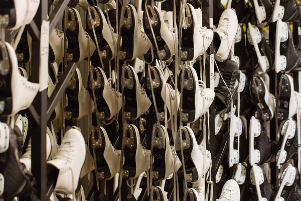 Rows of white and black ice skates, selective soft focus. Hire of winter sports equipment. Shelves with skates