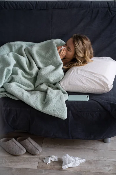 Femme malade à la maison couchée au lit souffrant d'allergie, symptômes de la grippe, fièvre, éternuements dans les tissus de papier — Photo