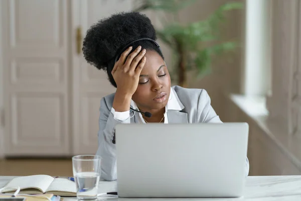 Cansado Afro funcionário de escritório com fones de ouvido dorme no local de trabalho, sofrendo de fadiga crônica — Fotografia de Stock