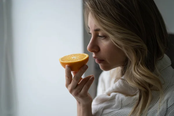 Nemocná žena se snaží vycítit vůni napůl svěží pomeranče, má příznak Covid-19, ztráta čichu, chuť — Stock fotografie