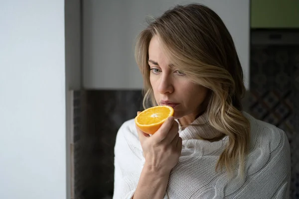 Sjuk kvinna försöker känna lukten av halv färsk apelsin, har symptom på Covid-19, förlust av lukt, smak — Stockfoto