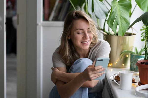 스마트 폰을 사용하고, 비디오 채팅을 하고, 집에 앉아 소셜 네트워크를 통해 수다를 떨고 있는 행복 한 여성. — 스톡 사진