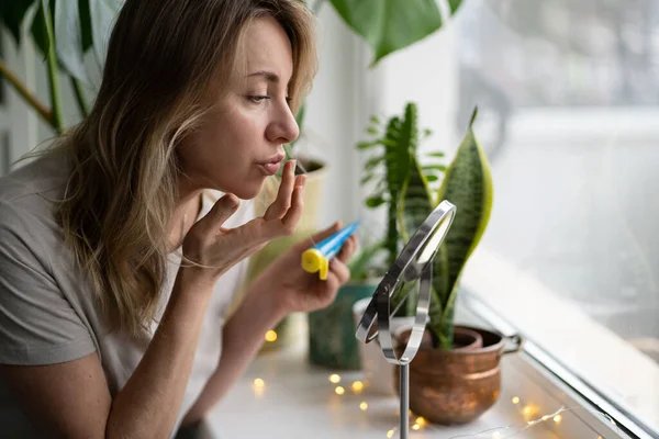 Femme appliquant un baume nourrissant hydratant sur ses lèvres avec le doigt pour prévenir la sécheresse et le gercement — Photo