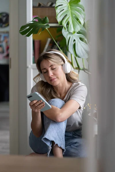 Mulher ouvindo música, usar fones de ouvido sem fio, usando telefone inteligente, conversando em redes sociais — Fotografia de Stock