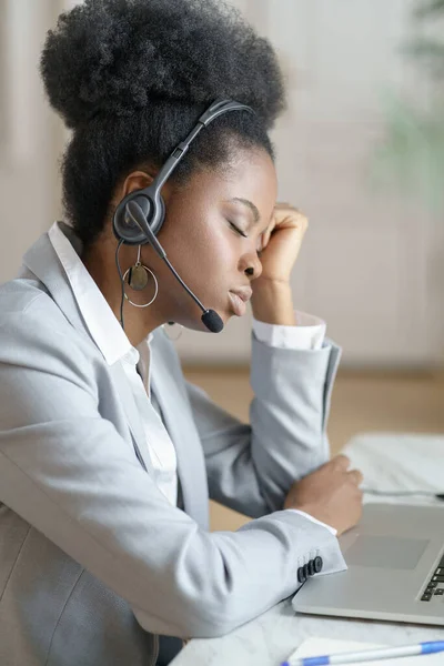 Müder Afro-Büroangestellter mit Kopfhörern schläft am Arbeitsplatz und leidet unter chronischer Müdigkeit — Stockfoto