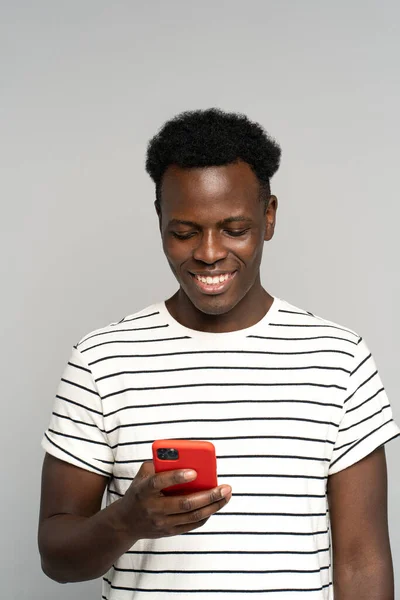 Glücklicher afrikanischer Millennial-Mann mit Brille, Handy in der Hand, isoliert auf studiograuem Hintergrund — Stockfoto