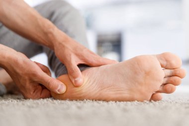 Man hands giving foot massage to yourself after a long walk, suffering from pain in heel spur, close up, indoors. Flat feet, leg fatigue, plantar fasciitis,  clipart
